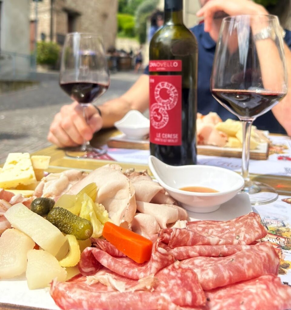 Tagliere di salumi e formaggi tipici con un calice di vino rosso